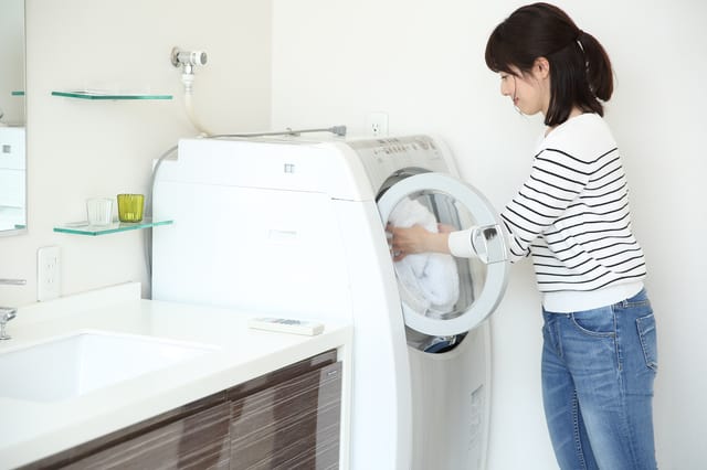ドラム式洗濯機で洗濯する女性